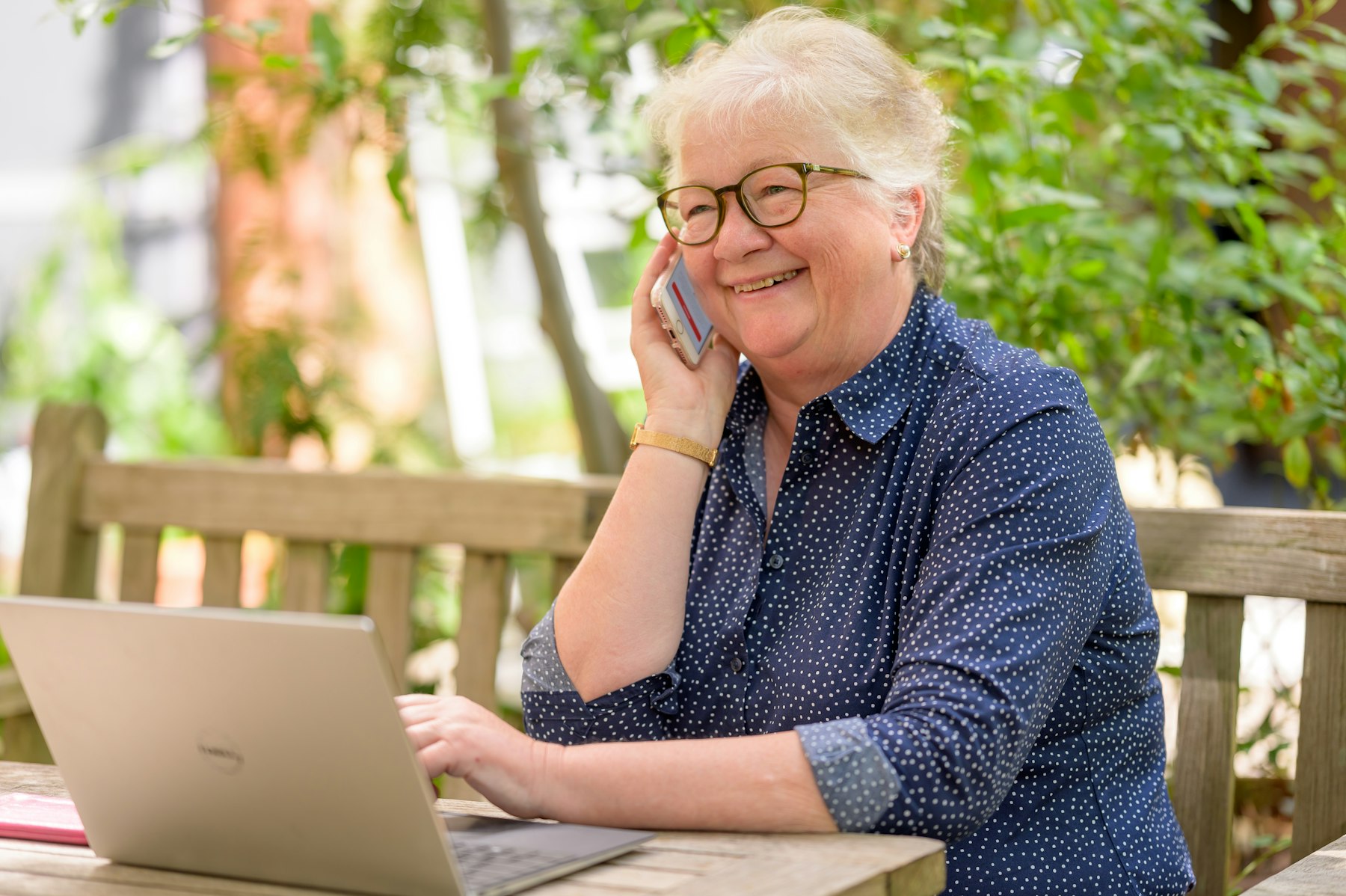 Senior woman on the phone while using a laptop